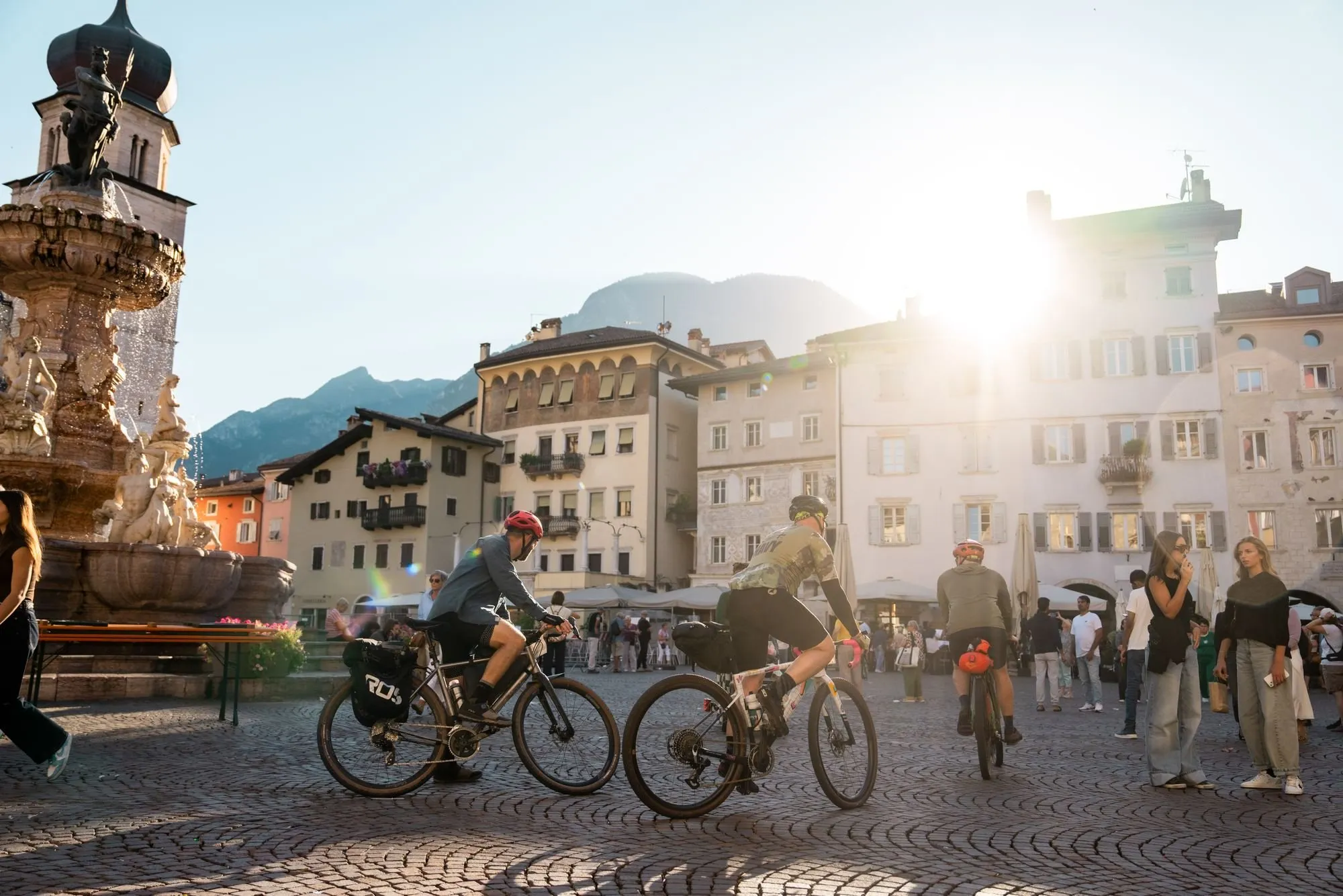 Ciclisti con le bici da gravel in piazza del Duomo a Trento, controluce